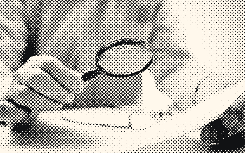 Une personne examine un document à la loupe.