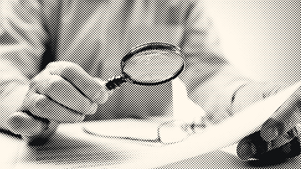 Une personne examine un document à la loupe.