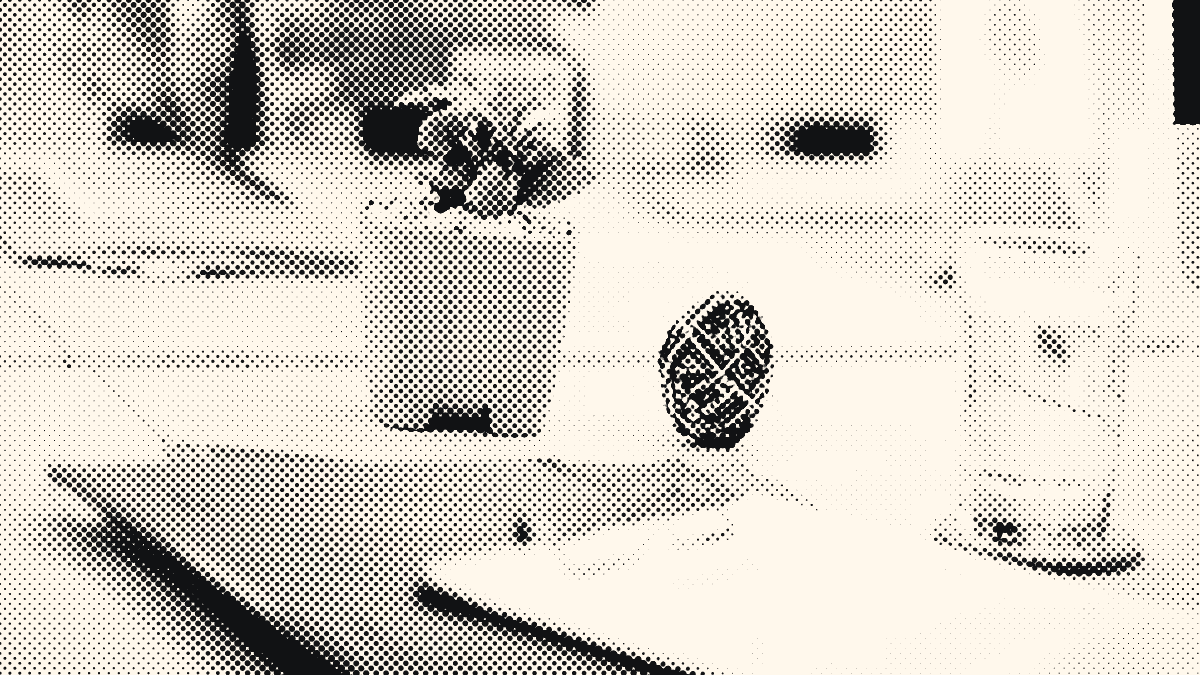 Un bureau avec une plante en pot, une balle d’élastiques et un verre d’eau.